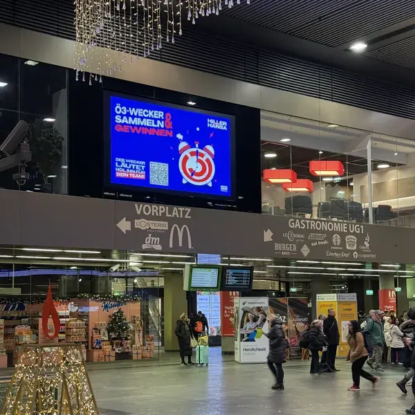 DOOH screen in a station concourse showing the Ö3 Wecker Challenge
