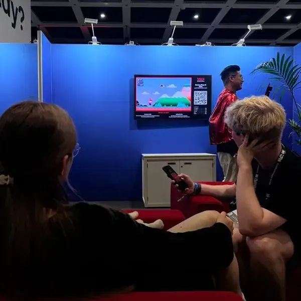Visitors play on the WeAreDevelopers booth screen with their phones